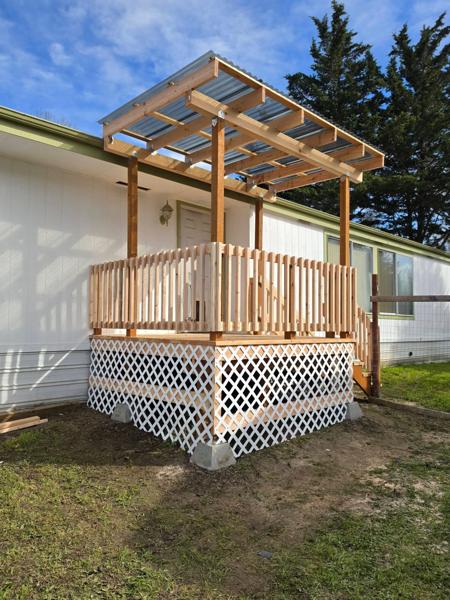 New cedar entry deck with corrugated metal canopy and lattice skirting