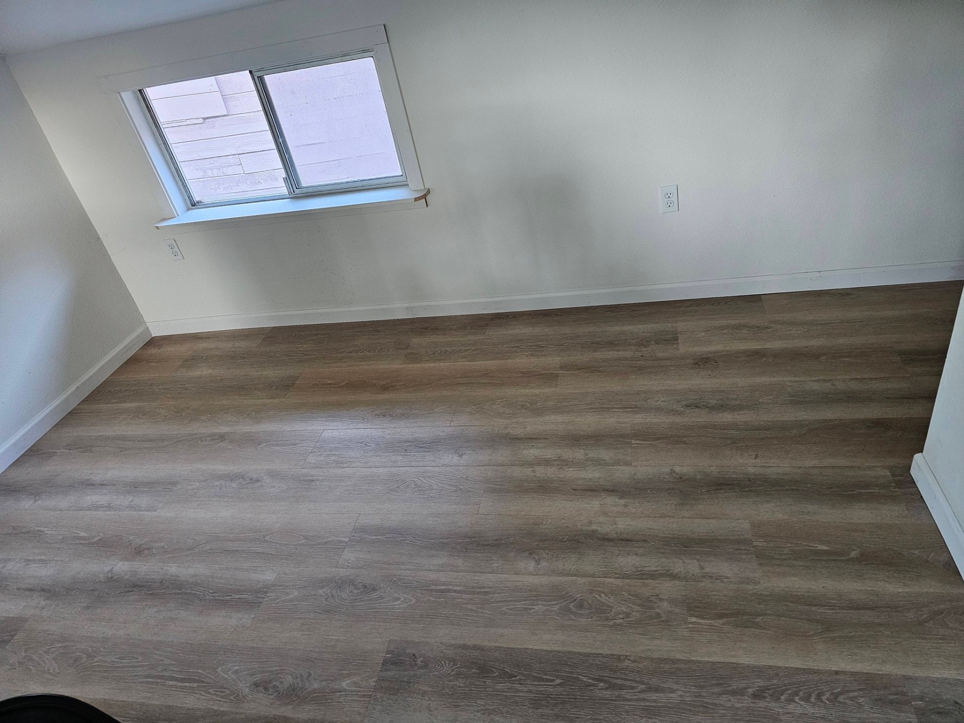 Bedroom with freshly installed wide-plank vinyl flooring and clean white walls