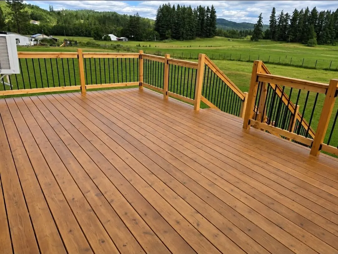 Freshly stained cedar deck with metal balusters overlooking a green pasture