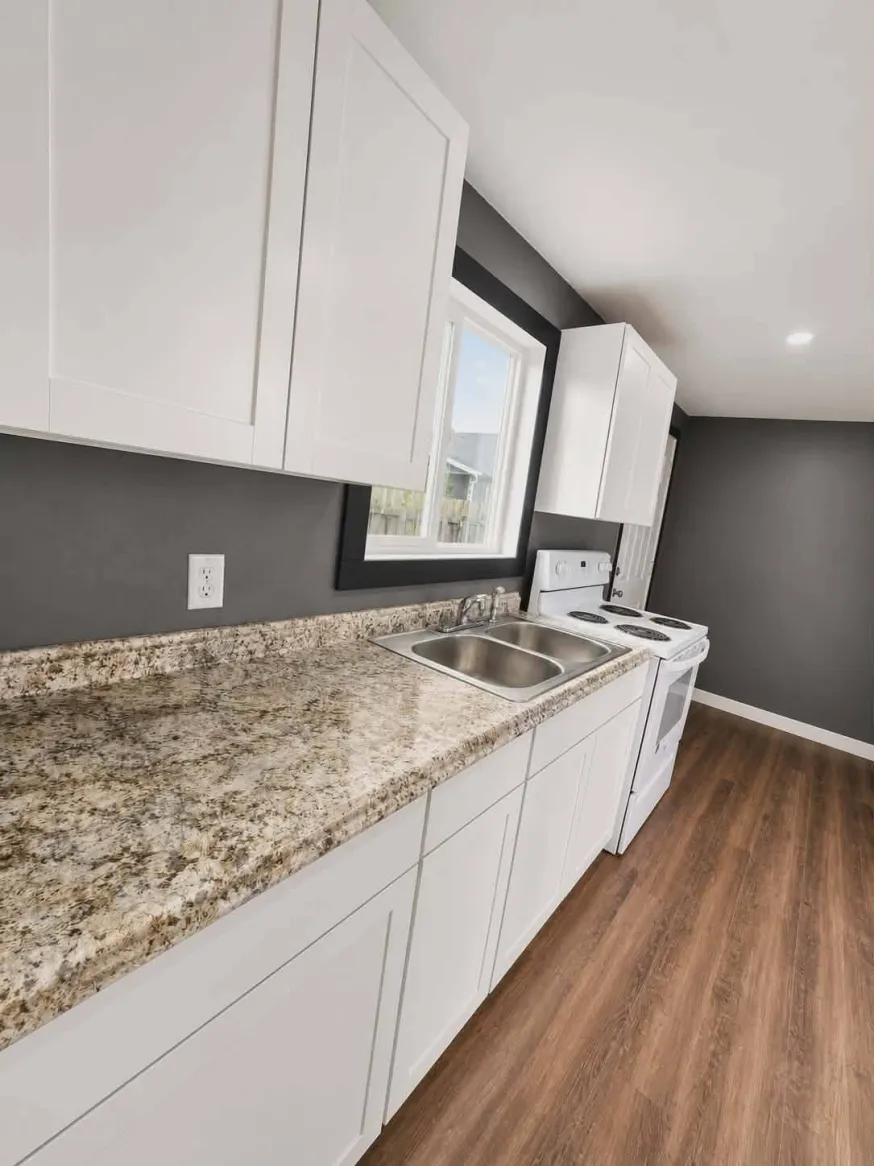Galley kitchen with white shaker cabinets, granite counters, and charcoal accent wall