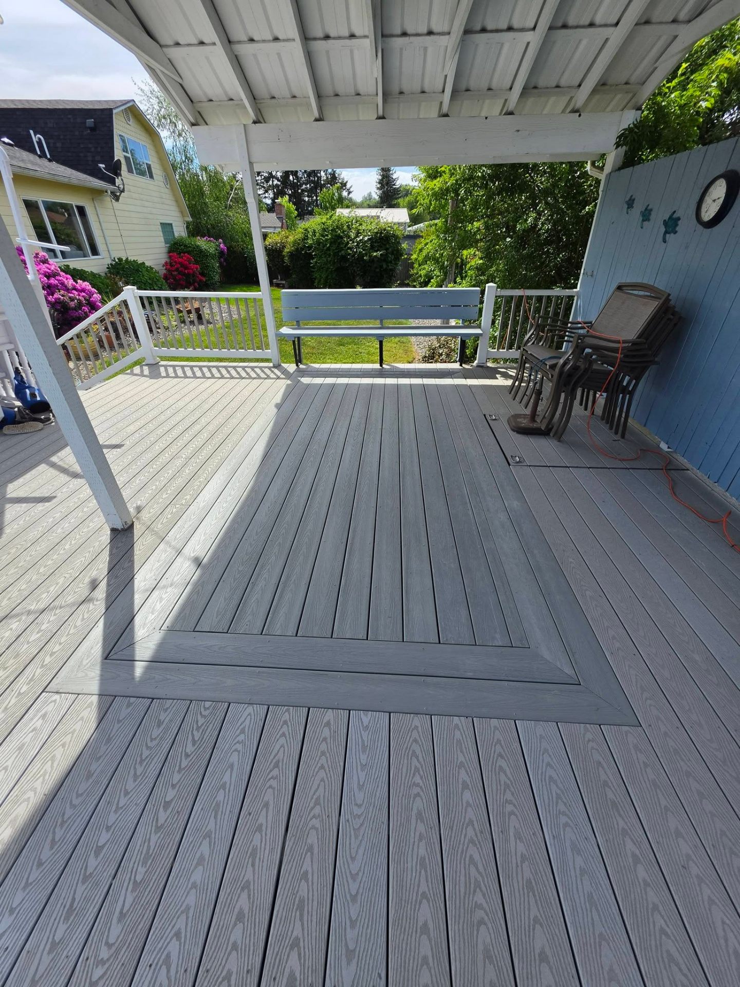 Covered backyard deck with two-tone gray composite decking and bordered inlay
