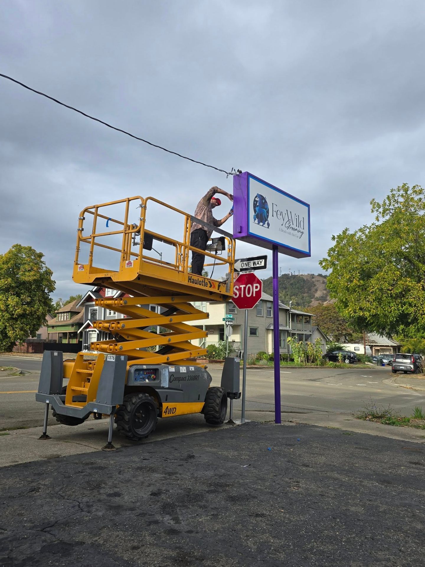 Crew installing an illuminated business sign from a scissor lift