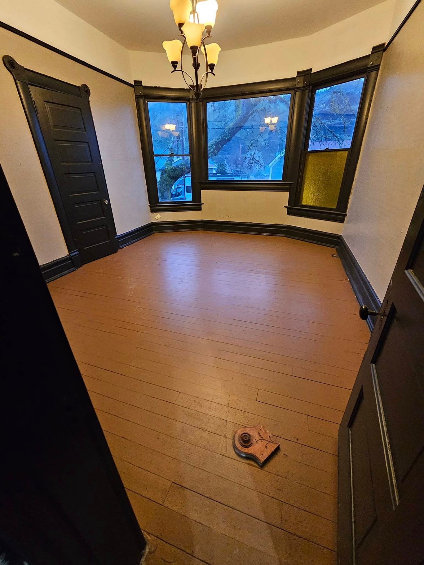 Restored Victorian parlor with original trim, chandelier, and refinished wood floor